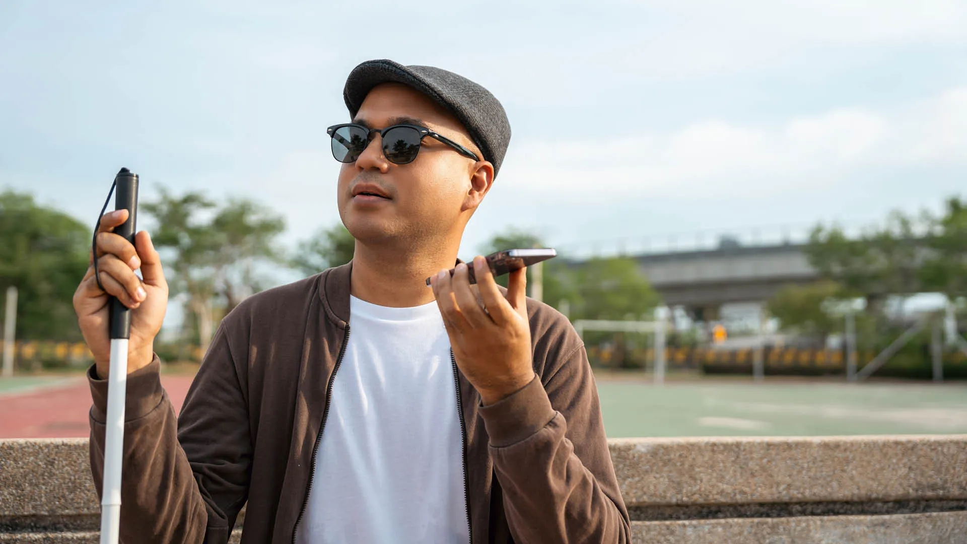 Blinder junger Mann hört, telefoniert mit einem Smart-Phone