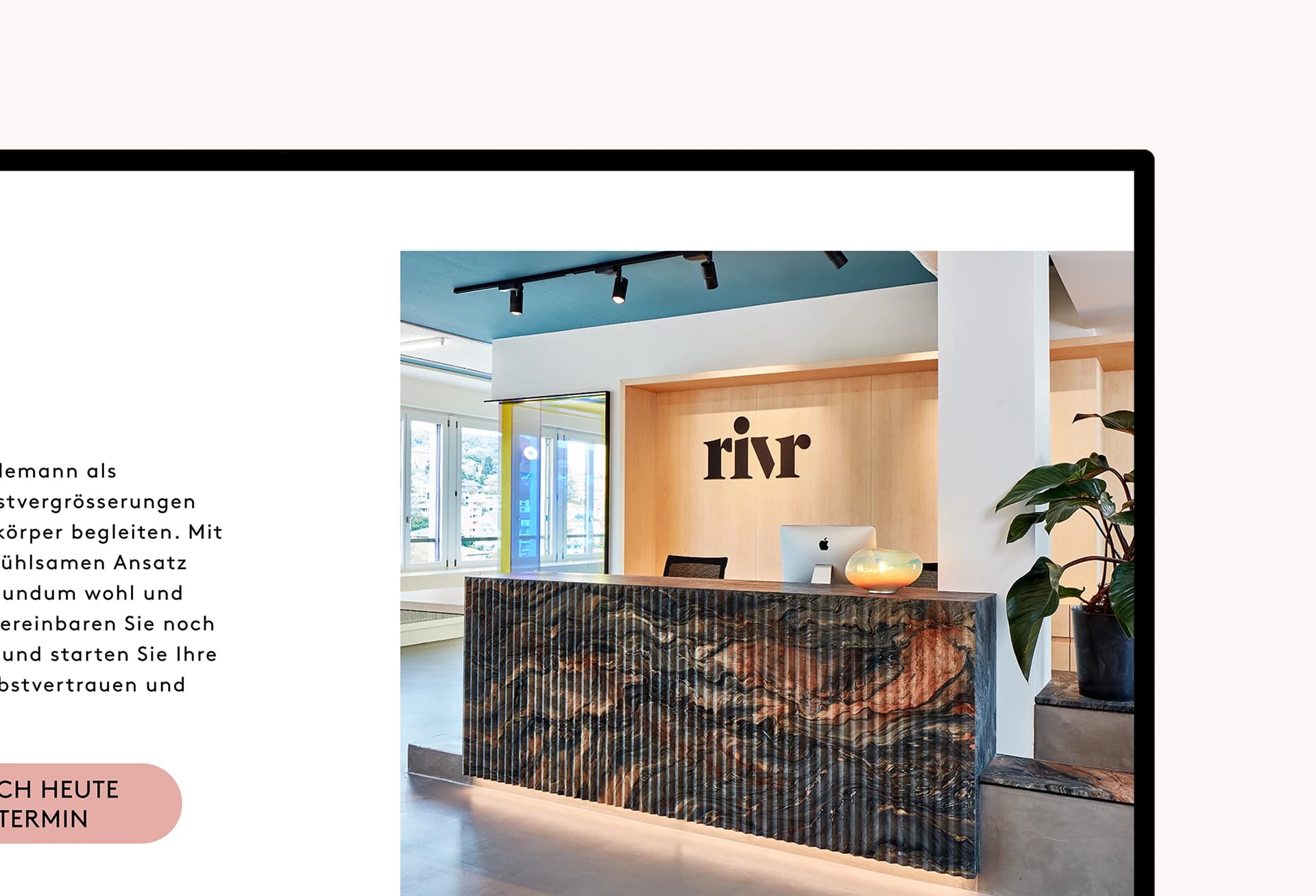 Empfangsbereich des rivr Campus mit modernem Marmortresen, iMac und Logo an der Holzrückwand.